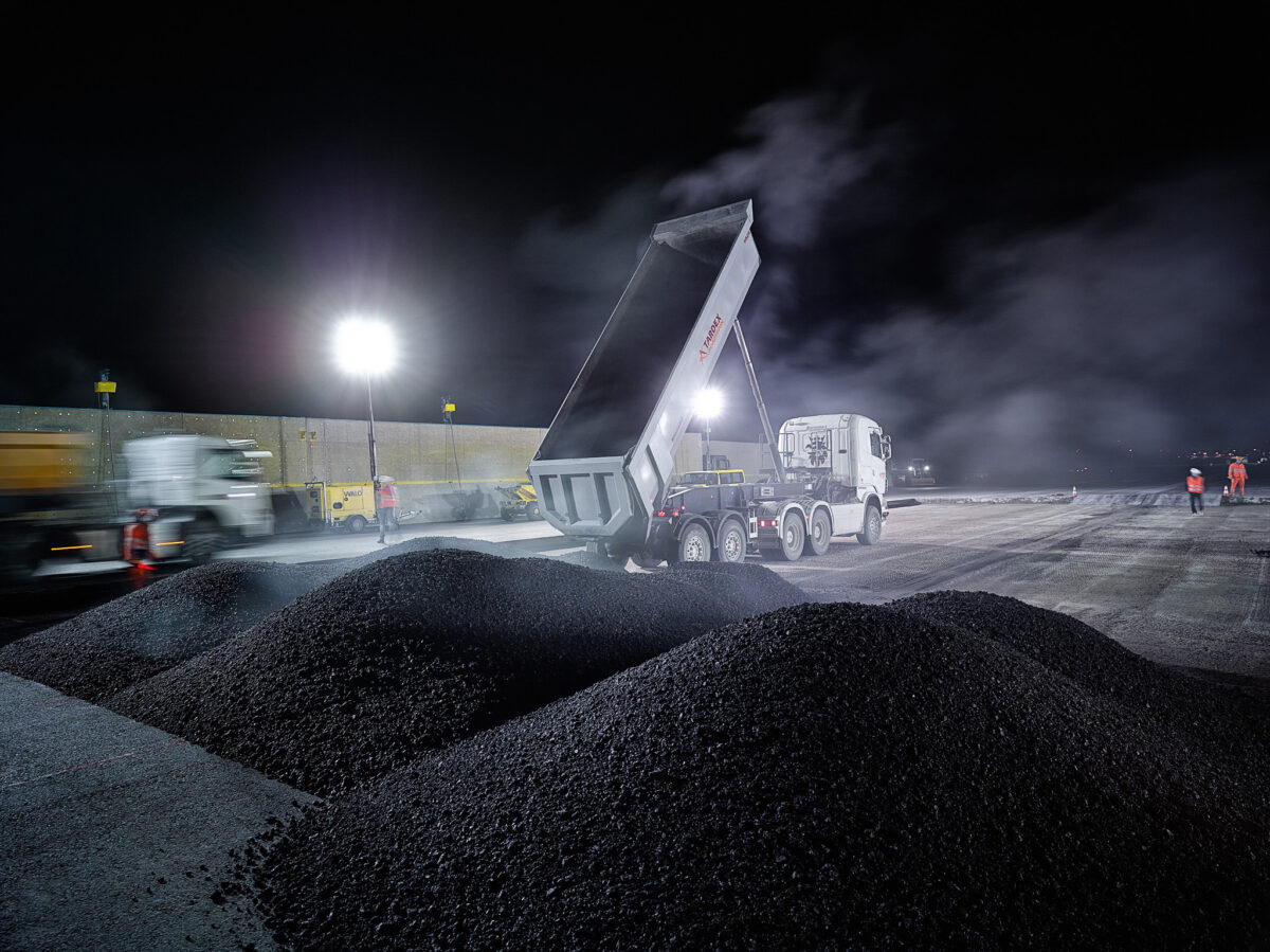 Asphalt paving machine laying a new runway surface at night at Zurich Airport, engineering photography by Scanderbeg Sauer
