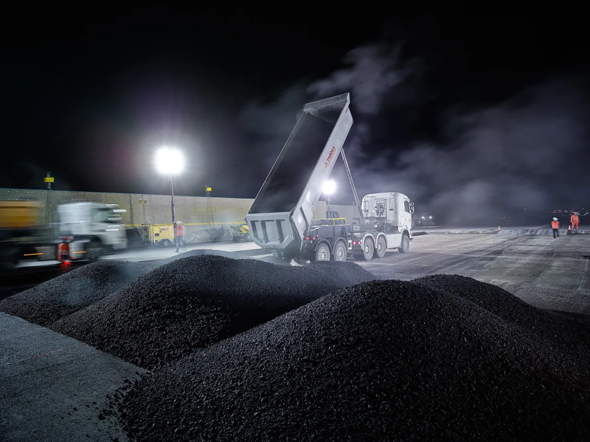 Asphalt paving machine laying a new runway surface at night at Zurich Airport, engineering photography by Scanderbeg Sauer