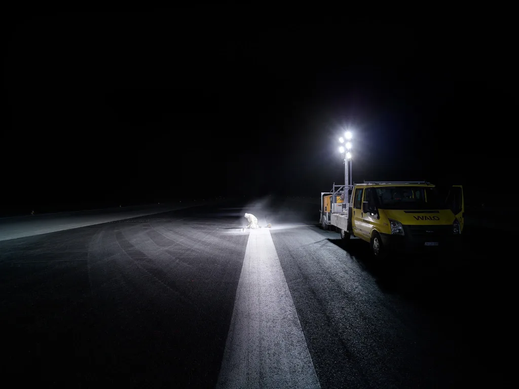 Service vehicle and floodlights on the runway at night during resurfacing works at Zurich Airport, engineering photography by Scanderbeg Sauer