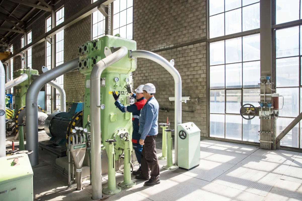 Technician working on a reciprocating compressor in a daylit production hall, Burckhardt Compression, Winterthur, industrial photography by Scanderbeg Sauer