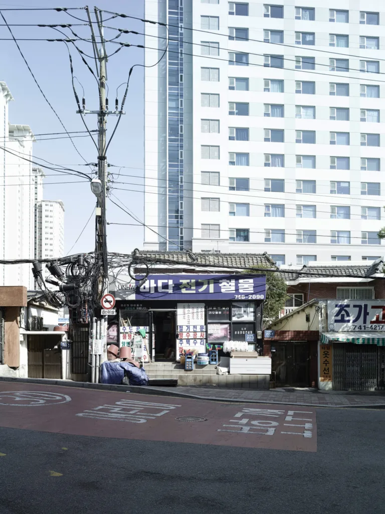 Old shops beneath a residential high-rise, Busan, South Korea, street photography by Scanderbeg Sauer