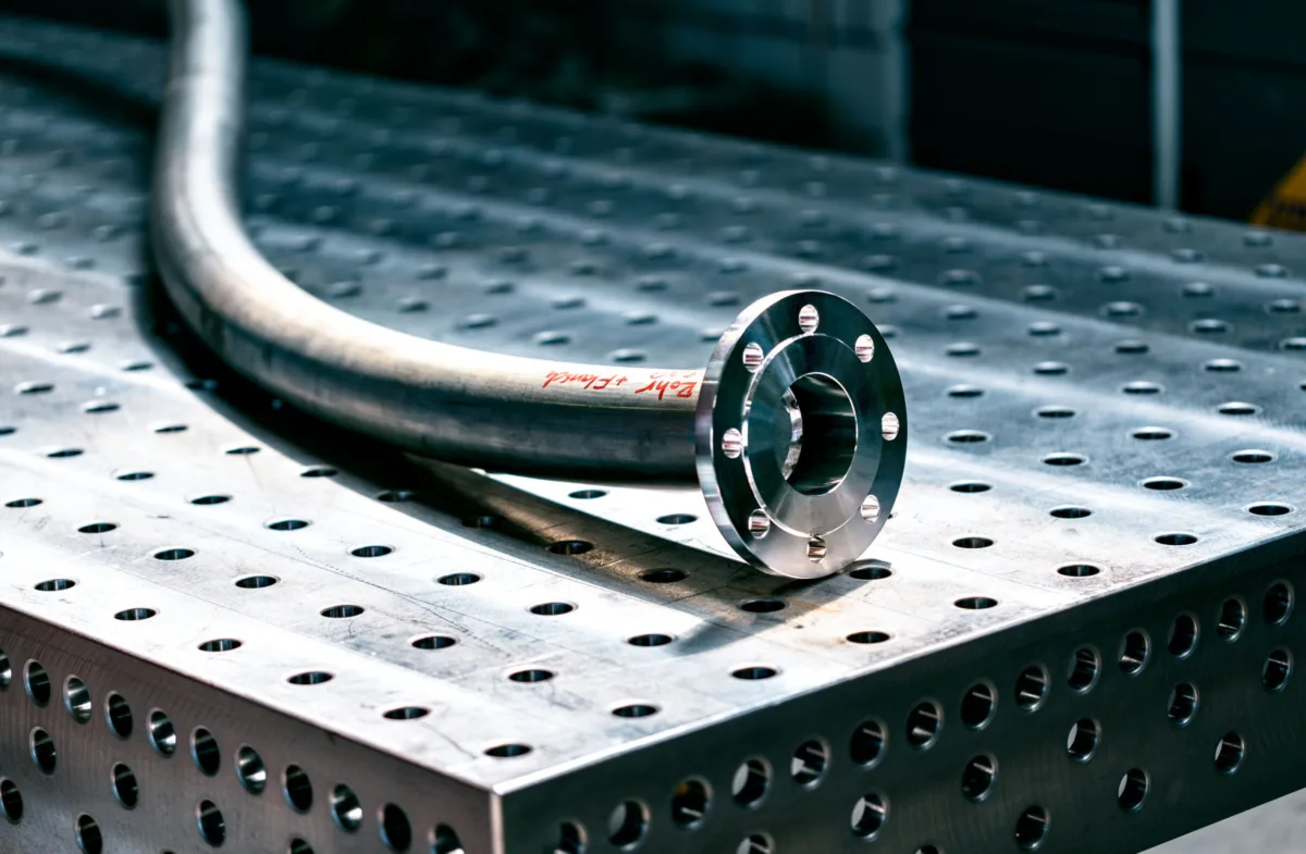 Gebogenes Rohr mit Flansch auf dem Schweißtisch bei Mechtop, Wangen bei Olten, Schweiz, Industriefotografie von Scanderbeg Sauer