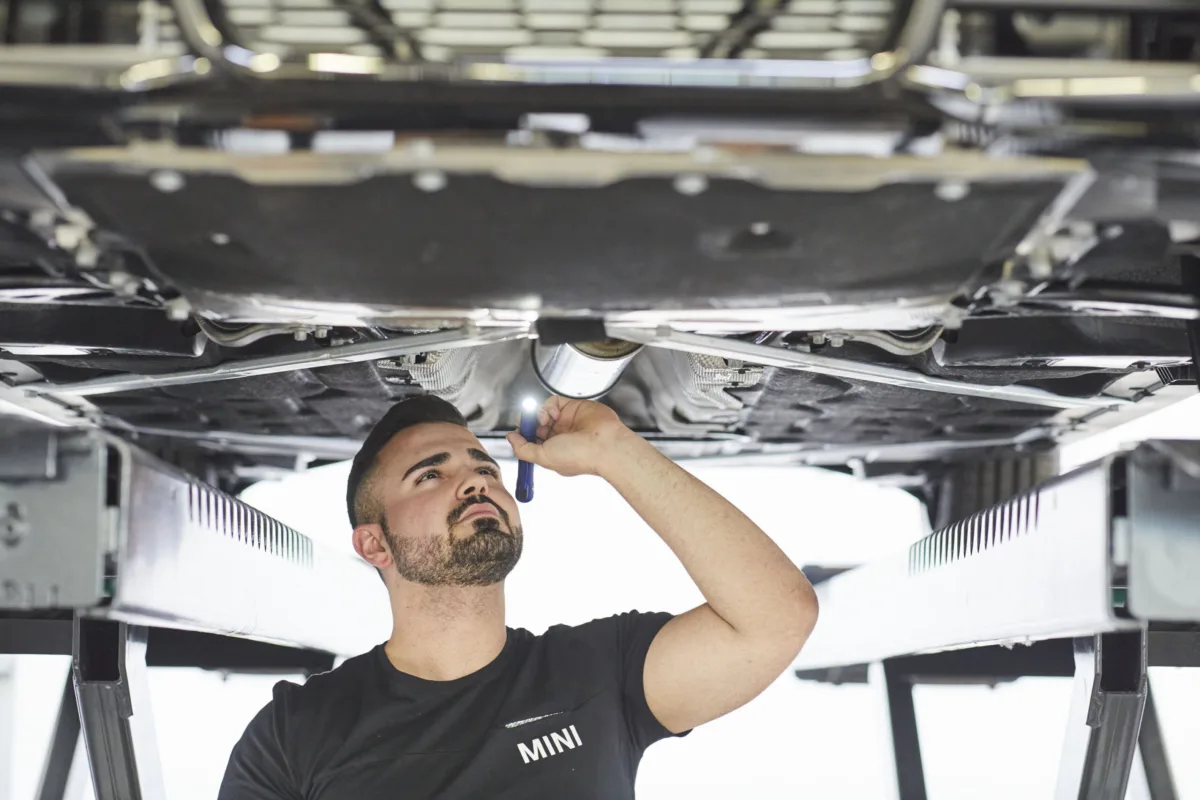 Servicetechniker bei der Fahrzeuginspektion auf der Hebebühne bei MINI Schweiz, Unternehmensfotografie von Scanderbeg Sauer