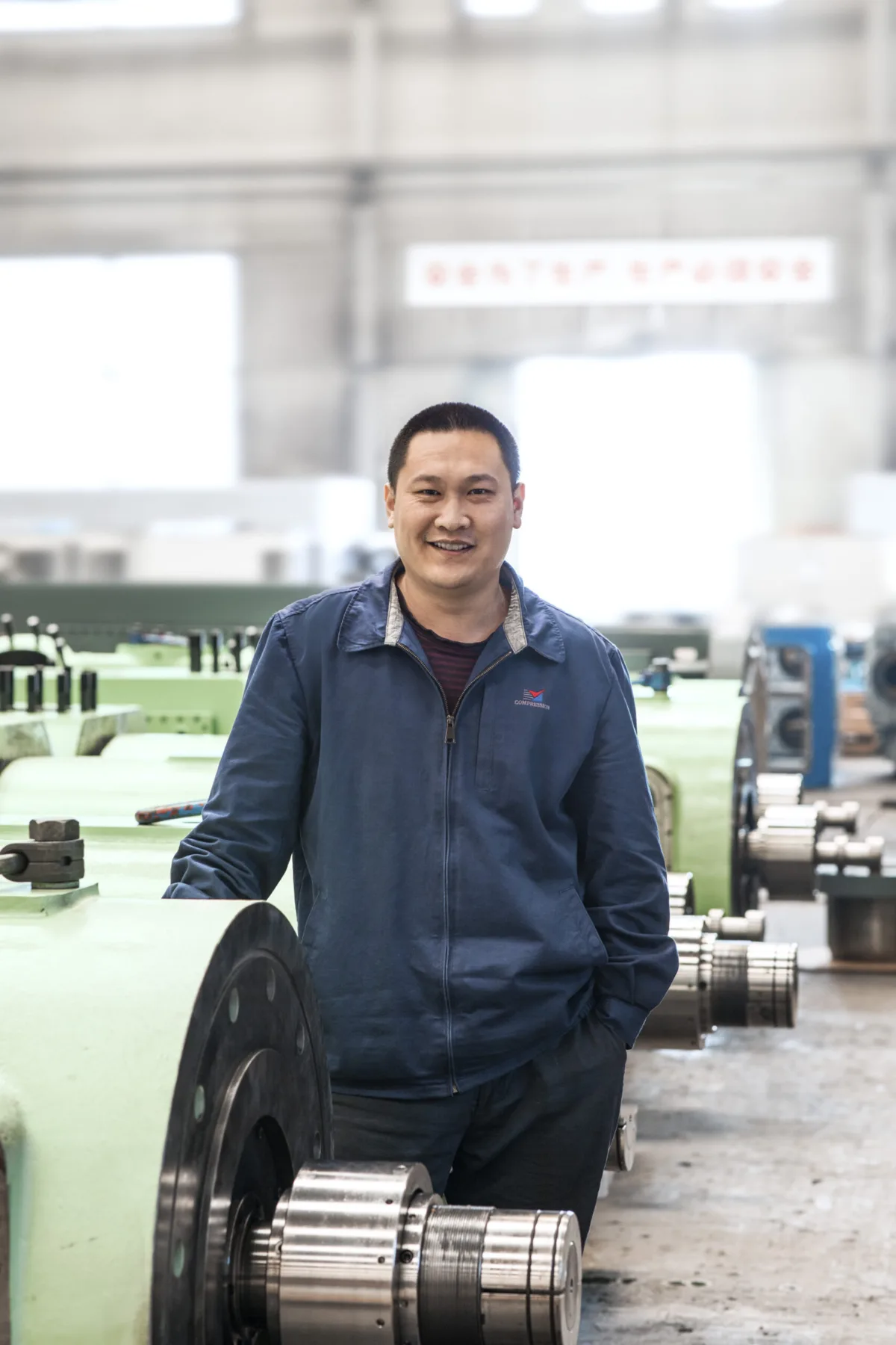 Employee portrait in the workshop with machined components, Shenyang Yuanda Compressor, Shenyang, China, industrial photography by Scanderbeg Sauer