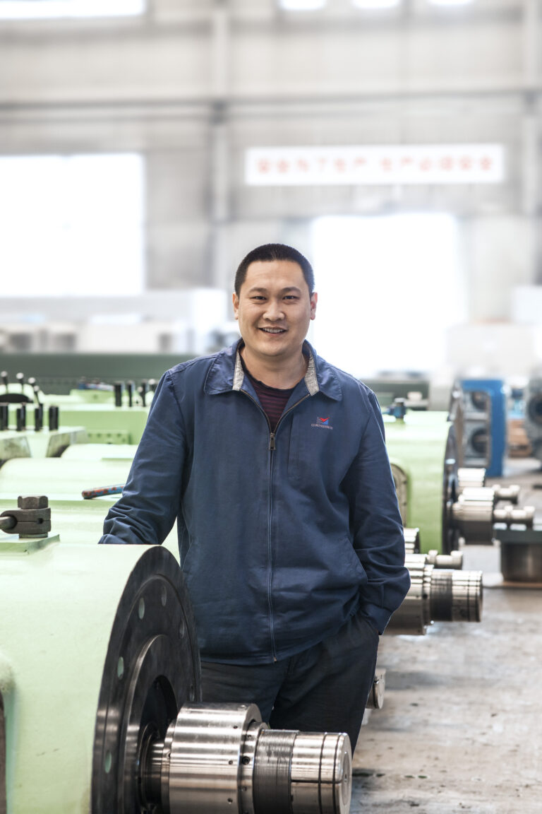 Employee portrait in the workshop with machined components, Shenyang Yuanda Compressor, Shenyang, China, industrial photography by Scanderbeg Sauer