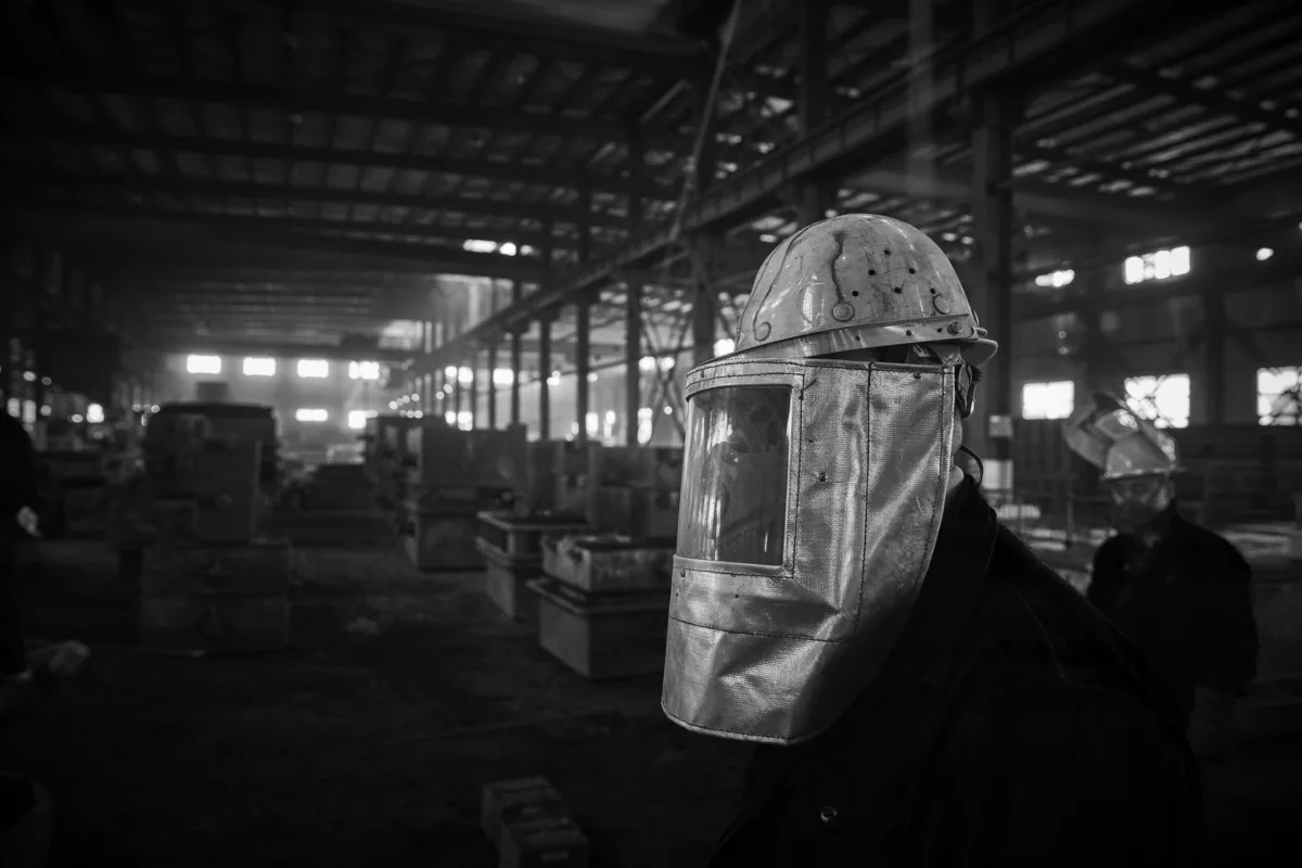 Black-and-white portrait of a foundry worker in a protective face shield, Shenyang Yuanda Foundry, Shenyang, China, industrial photography by Scanderbeg Sauer