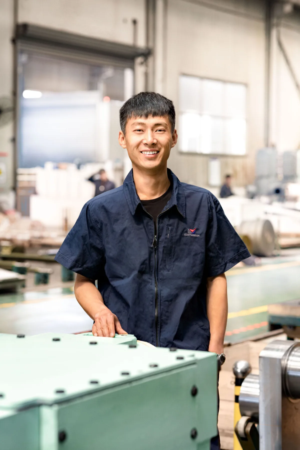 Employee portrait by a compressor component in the workshop, Shenyang Yuanda Compressor, Shenyang, China, industrial photography by Scanderbeg Sauer