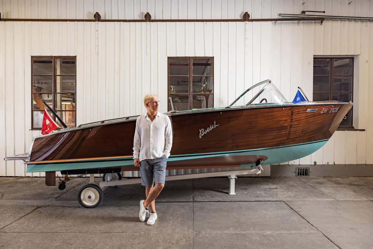 Mann steht neben einem Boesch Mahagoni-Motorboot auf einem Trailer vor der Bootswerft, Boesch Kilchberg, Bootsfotografie von Scanderbeg Sauer