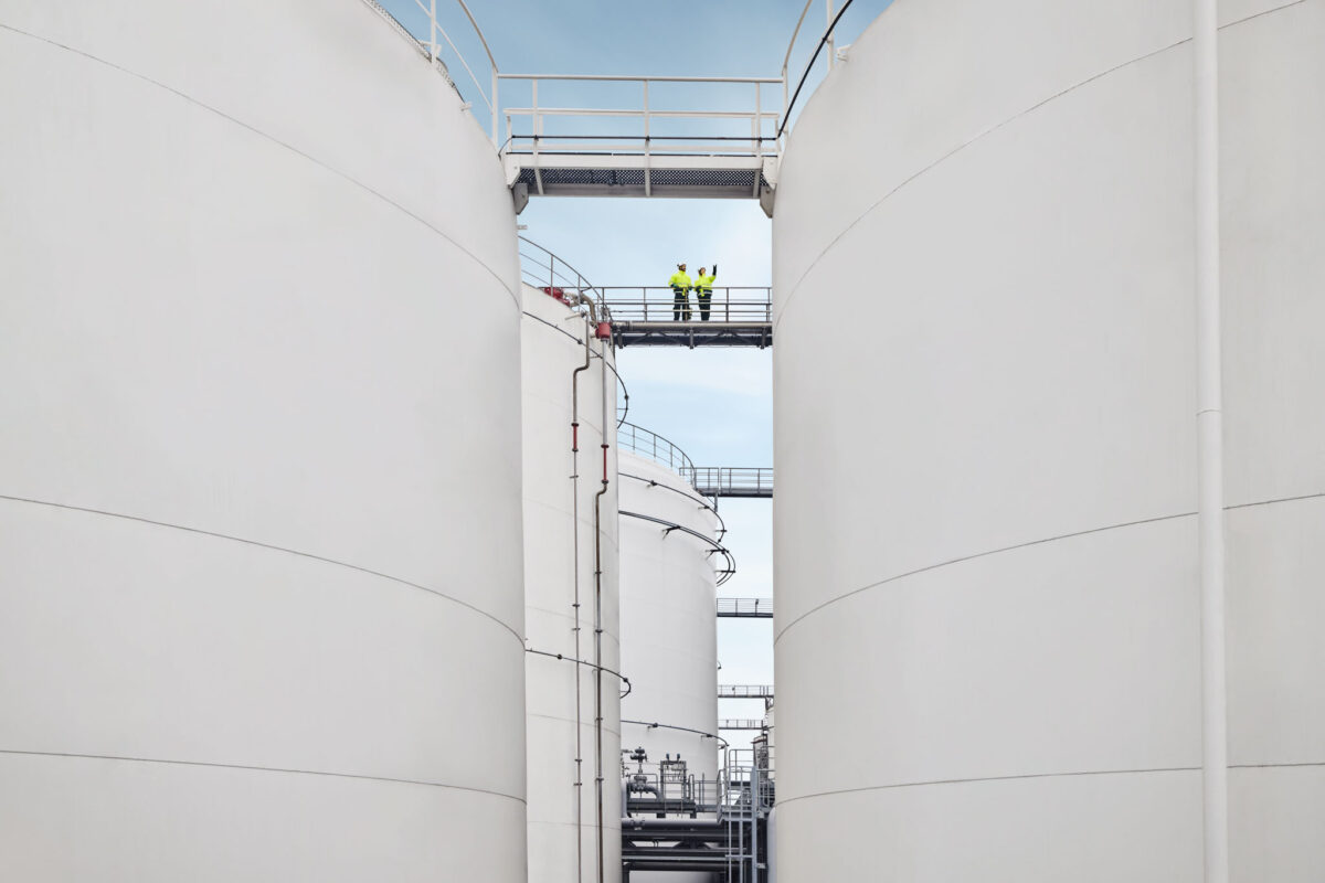 Two people on a connecting bridge between storage tanks at Ambrian Energy Bremen, industrial photography by Scanderbeg Sauer