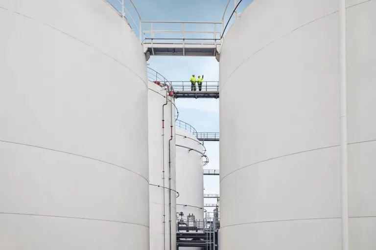 Two people on a connecting bridge between storage tanks at Ambrian Energy Bremen, industrial photography by Scanderbeg Sauer