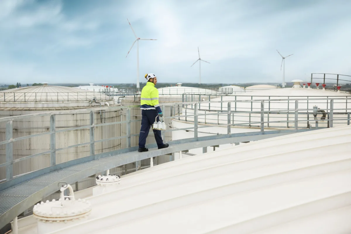 Worker on elevated walkway above industrial tanks at Ambrian Energy Bremen, industrial photography by Scanderbeg Sauer