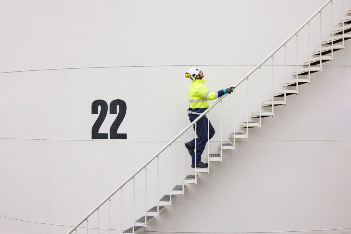 Worker climbing external staircase on industrial tank at Ambrian Energy Bremen, industrial photography by Scanderbeg Sauer