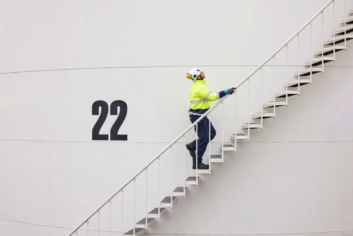 Worker climbing external staircase on industrial tank at Ambrian Energy Bremen, industrial photography by Scanderbeg Sauer