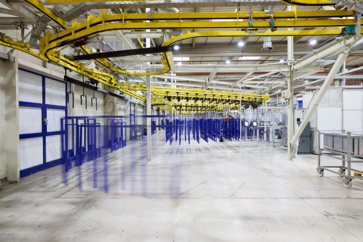 Wide view of coating facility hall with blue frames on conveyor system, Geberit, Lichtenstein, industrial photography by Scanderbeg Sauer